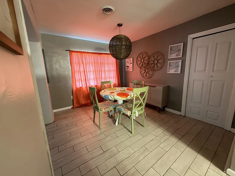 Dedicated dining nook with a round table for four, pendant lighting, and tile floors, set beside a window and storage cabinet