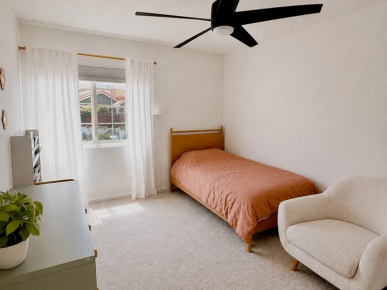 Bright and inviting secondary bedroom featuring abundant natural light, neutral finishes, ceiling fan, and generous closet space. Perfect for family members, guests, a home office, or flexible living needs.