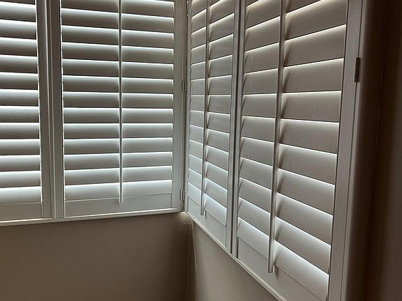 Corner window in living room with shutters.
