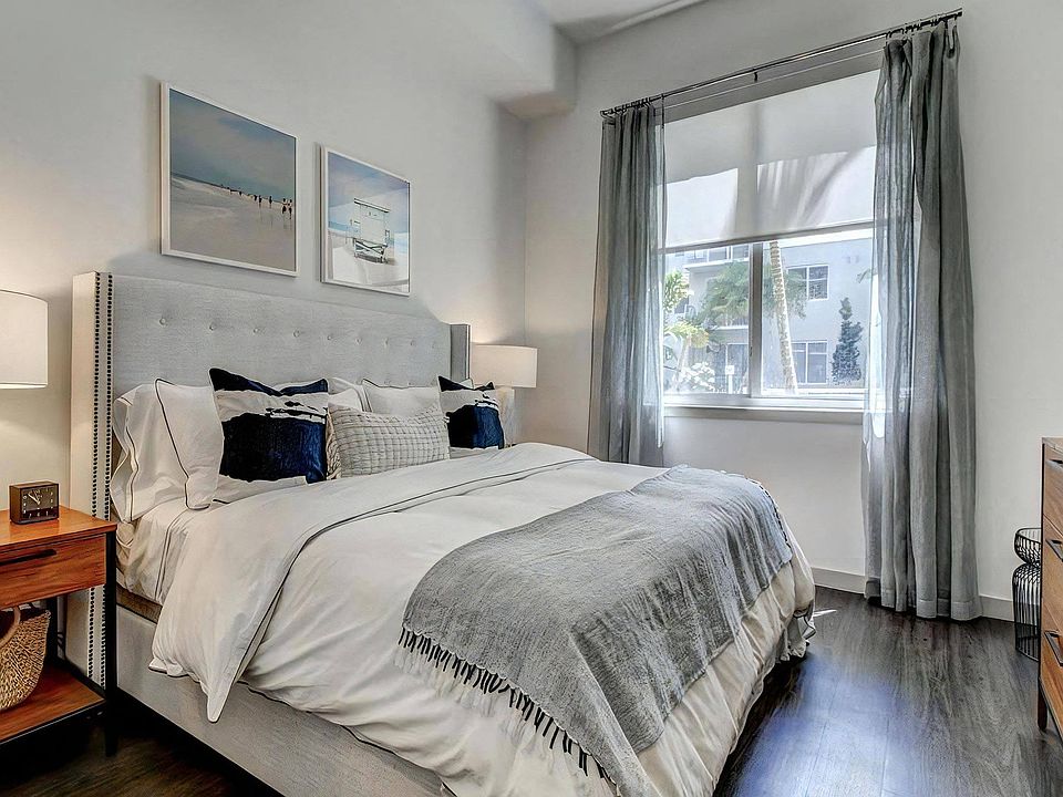 Apartment Bedroom With Dark Wood Floors and Window Facing Outdoor Landscaping
