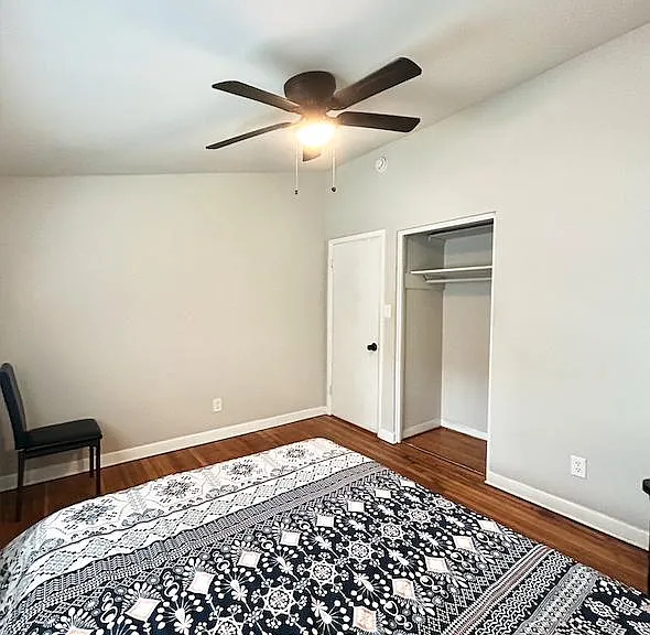 Spacious bedroom with hardwood floors, ceiling fan, and an open closet for convenient storage.