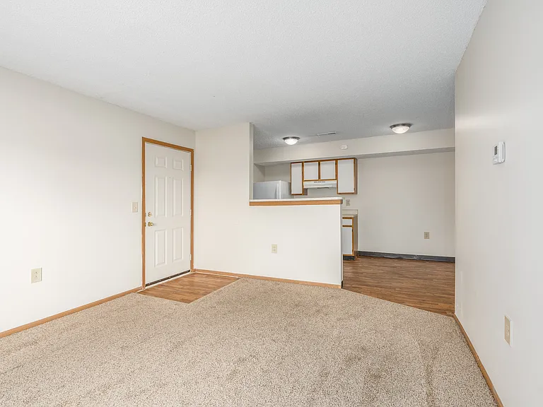 Main living area and kitchen of a River Valley apartment home in Lancaster, OH, with carpeting and cabinets.