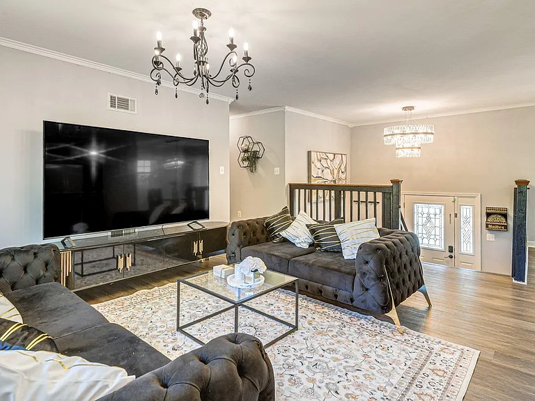 Spacious living room with oversized seating, large TV setup, and open sightlines to the entry and adjoining areas.