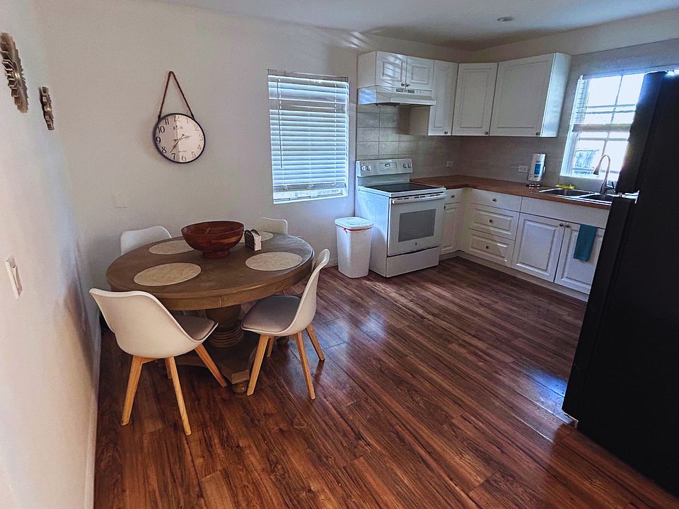 Spacious kitchen-dining area with a clock and excellent natural light.