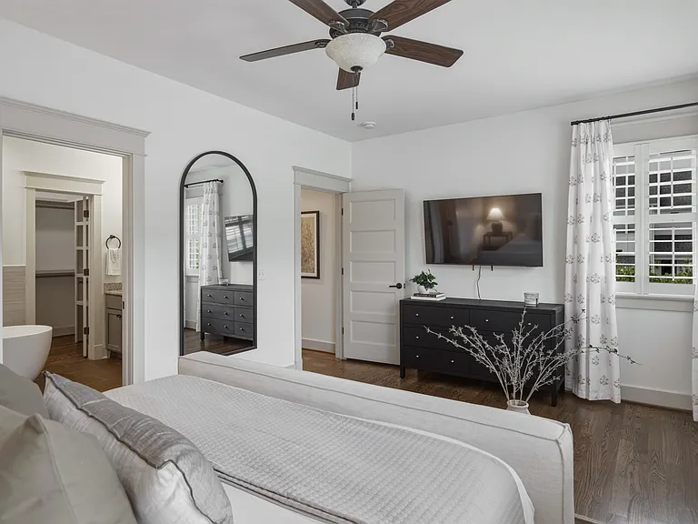 The primary suite features a king-sized bed, huge walk-in closet, ceiling fan, dresser, smart TV, and ensuite bathroom.