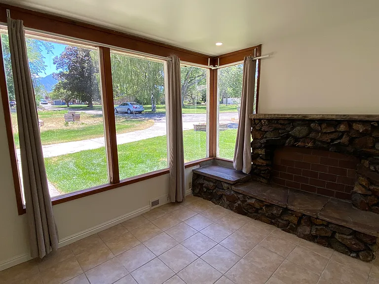 Living room view - 4 large windows with view of adjacent private park (not part of rental), but enjoy the view of mature trees and greenery. Living room has a decorative rock fireplace (not functional), mantle and seating.