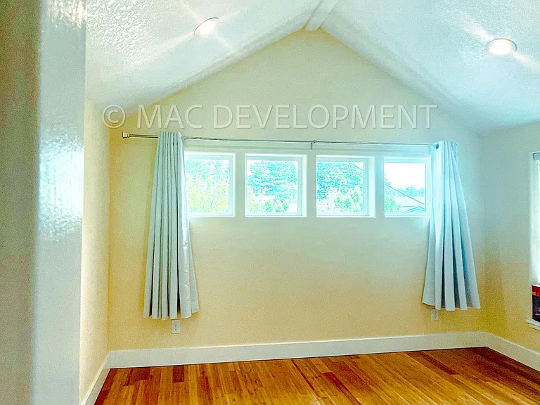 Vaulted ceiling in the bedroom along with East side tree view of Rocky Butte Natural Area.