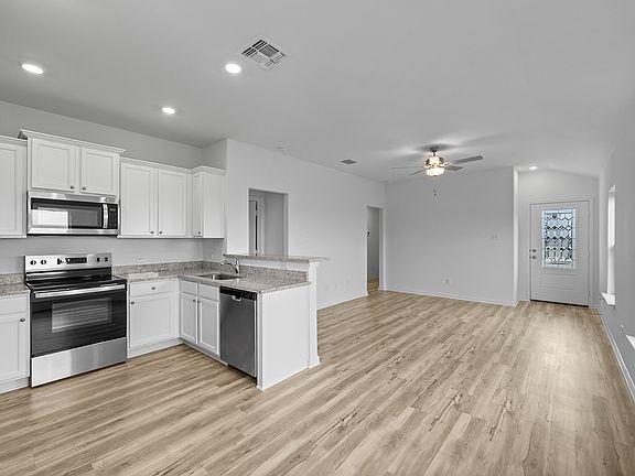 The kitchen features granite countertops and white cabinets