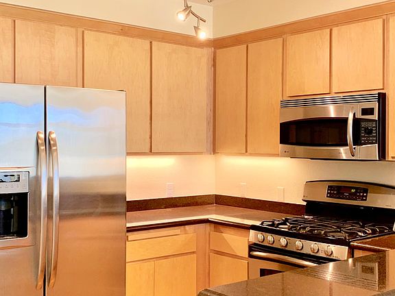 Modern Kitchen Features Designer Lighting, Stainless Steel Appliances and Gas Range