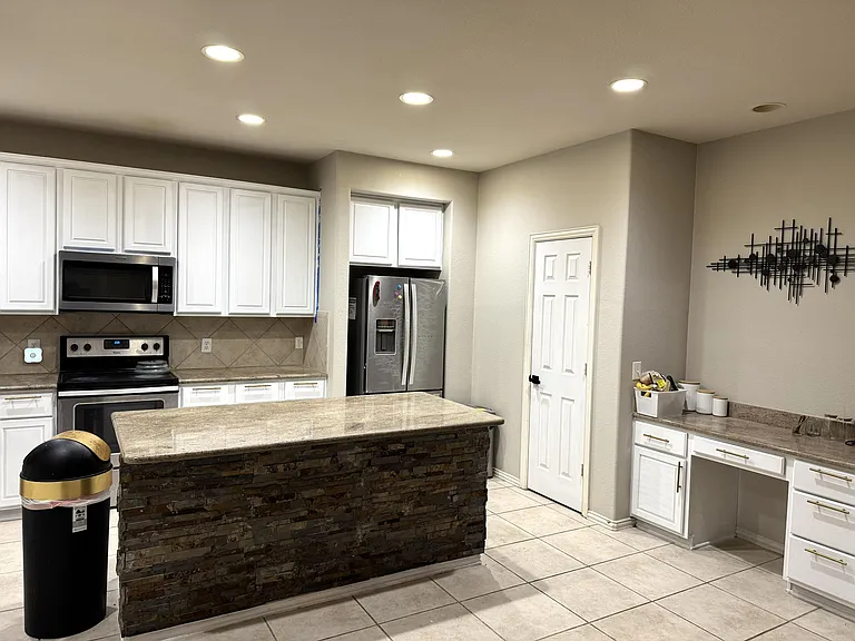 Spacious kitchen with a large island, ample white cabinetry, tile flooring, and stainless appliances including a side-by-side
