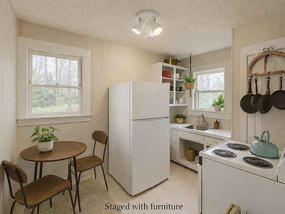 Cozy kitchen with full size refrigerator, electric stove, and disposal. Room for small breakfast table. Furniture is staged