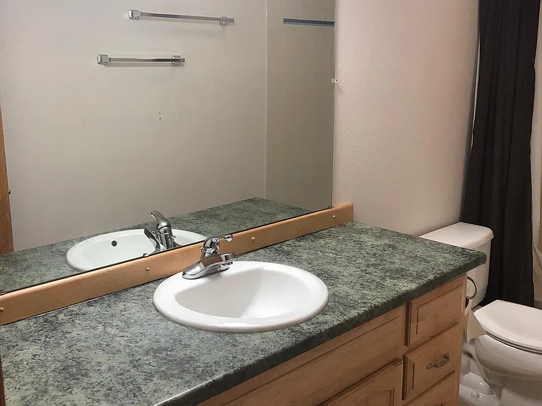 Large spacious full bathroom with a large lighted mirrored countertop, sink, paneled work cabinets.