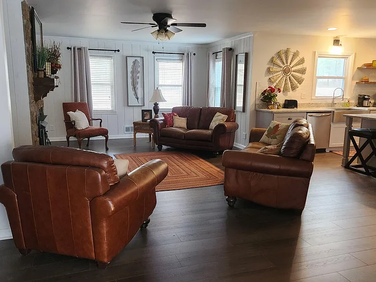 Open-concept living area with leather seating, ceiling fan, and easy flow into the kitchen with breakfast bar.