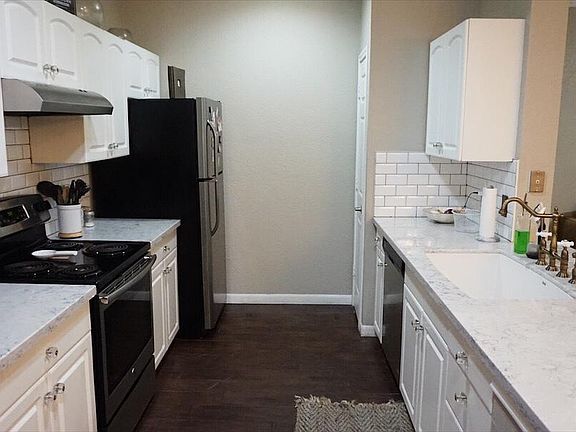Full kitchen view. All stainless appliances (dishwasher, refrigerator, stove) quartz countertops, white subway tile, wood tile floors & pantry.