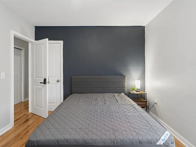 Private bedroom with hardwood floors, a full bed, and convenient bedside table with lamp for nighttime comfort.