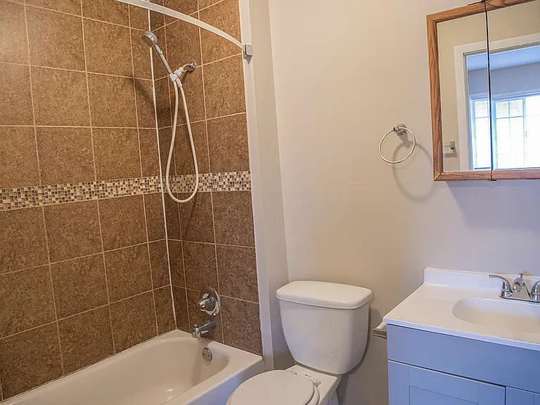 Inviting bathroom with elegant brown tile design, featuring a chic vanity, modern shower, and natural light through a window.