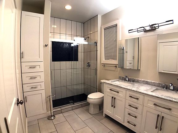 Double vanity bathroom with walk in shower and storage