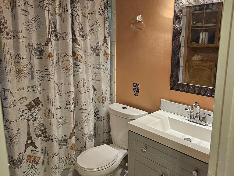 Full bath with shower/tub combo, tiled flooring, and a single-sink vanity with storage and framed mirror.