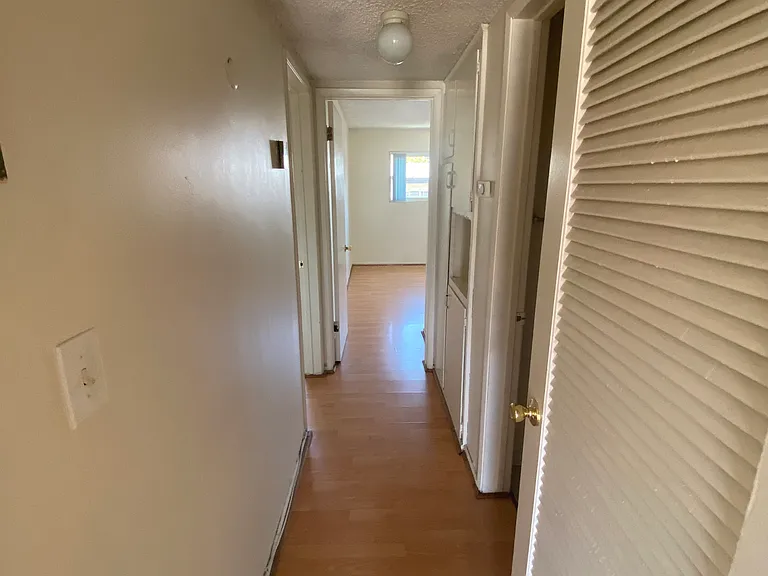 View of hall way leading to master bedroom on left, second bedroom straight ahead and bathroom and storage cabinets on right.