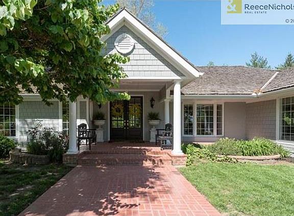 Wide, brick sidewalk leads to double doors at the front of the house.