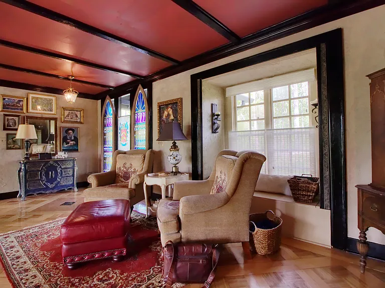 Upper mezzanine where front door is located overlooking the 2 story living room and wooded views; Both bedrooms flank this space