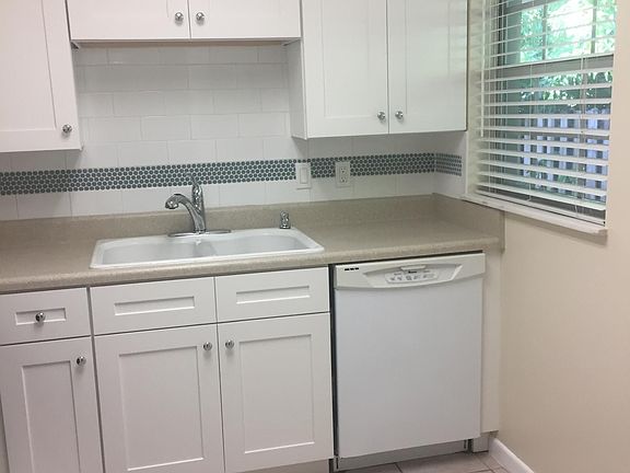 New white shaker wood cabinets, subway tile backsplash, and Formica countertop.