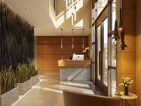 Gorgeous two-story lobby with concierge counter, decorative wall and chandelier.