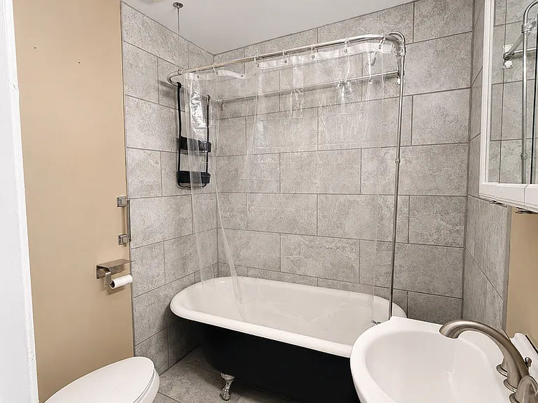 The bathroom features a charming clawfoot-style soaking tub with shower setup, white vanity, mirrored medicine cabinet, updated lighting, and neutral wall colors.