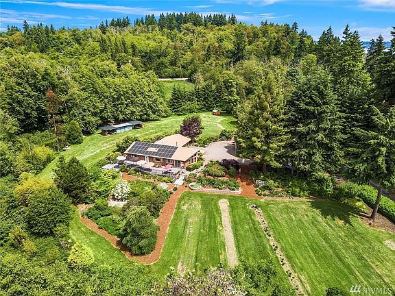 Aerial view taken from south of home looking north. Photo shows outbuildings and field beyond. Property extends all the way to the road in the distance.
