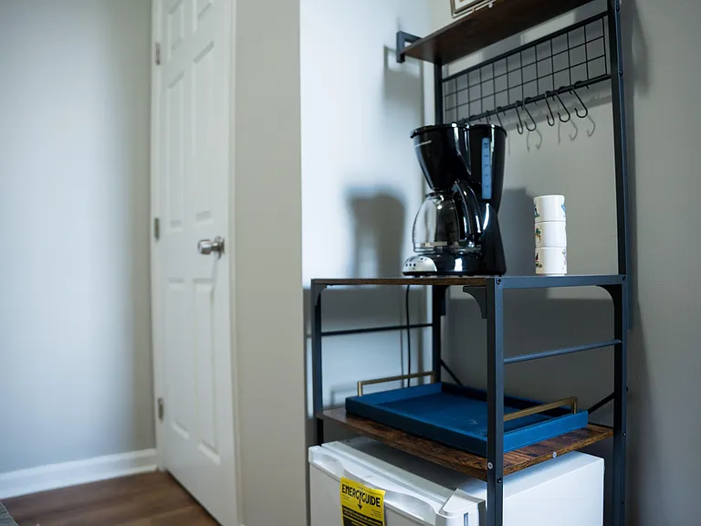 Convenient in-room beverage nook with shelving, mini fridge, and coffee maker for quick snacks and morning routines.