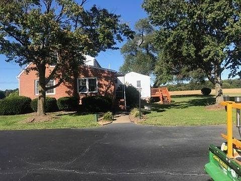 Side of house with steps leading to back door and master bedroom with porch (white siding).