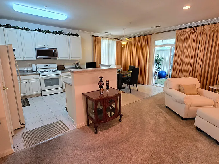 Sun-drenched, massive living room anchored by a cozy fireplace and framed by elegant, floor-to-ceiling drapery.