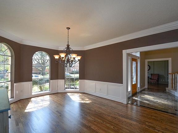 Elegant dining room to right of entry with wains coating and crown molding. Arched windows, updated chandelier and beautiful refinished wood floors.