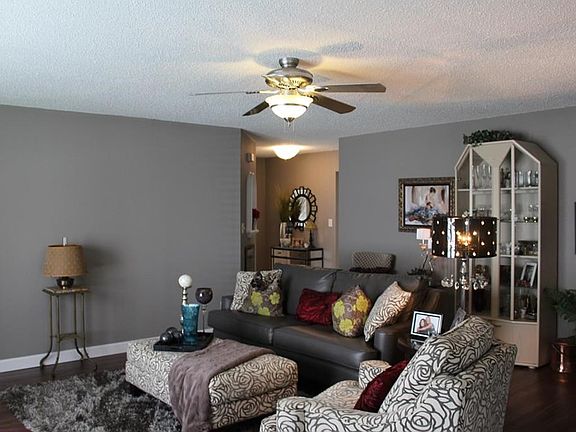Spacious great room with ceiling fan with light and newer laminate floor covering.