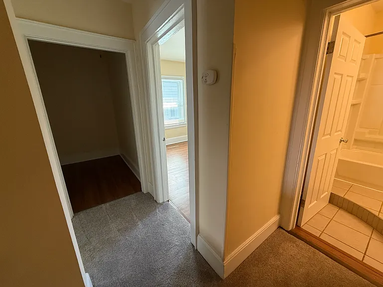 Upstairs hallway with brand new carpet, installed in 2025. To the right is the bathroom; a closet to the right is not shown. Rear bedroom shown. A large walk-in closet/storage area is shown.