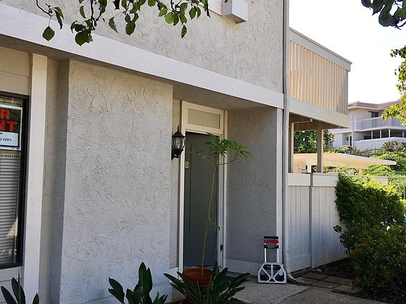 Front door and gate to patio with balcony above patio