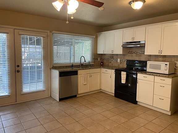 Spacious kitchen with granite and tile backsplash.