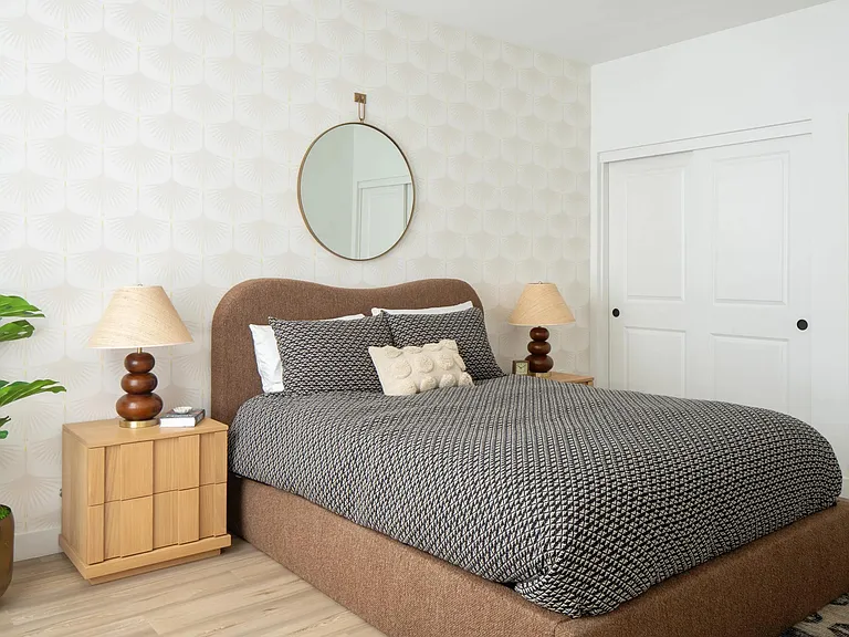 A calming bedroom retreat with textured wallpaper, warm wood tones, and layered neutrals for effortless comfort.