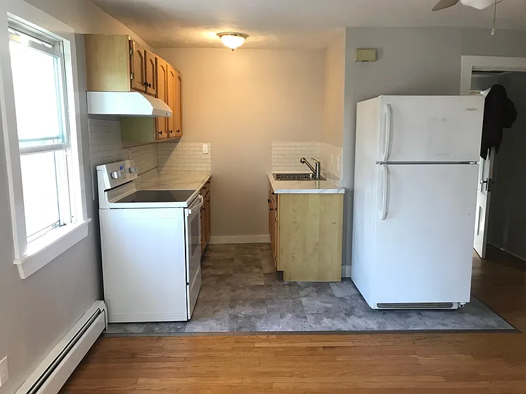 Open concept kitchen leads into living room area (hardwood floors).
