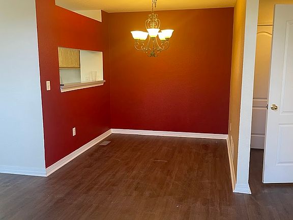 The dining room has bold red walls and a chandelier for over the table.