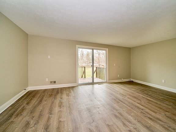 Large Great Room with New Laminate Floors and Sliding Glass Door to Small Deck and Huge Backyard