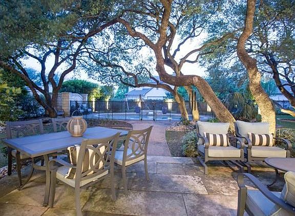 Walk out limestone patio from living to beautiful oaks & pool!