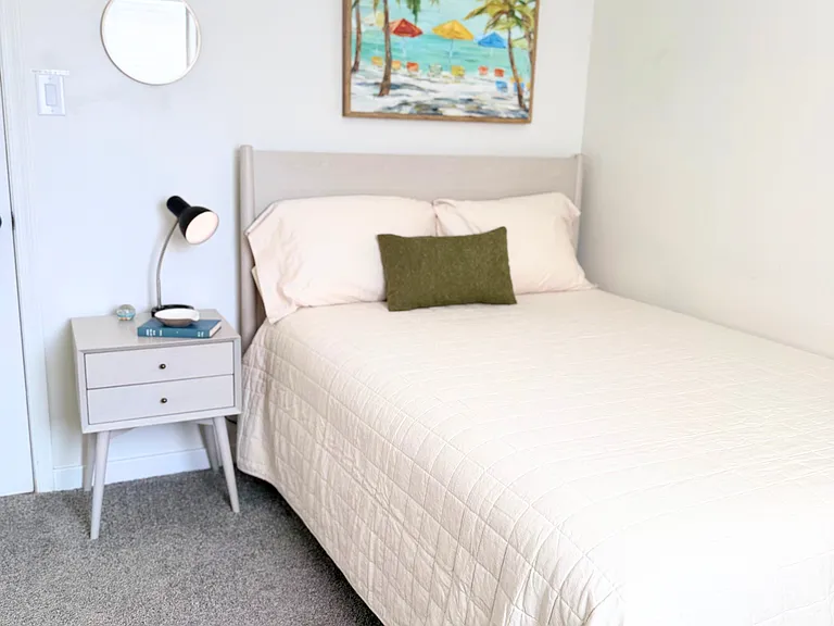 Cozy bedroom featuring a comfortable bed, dresser, nightstand, and ceiling fan.