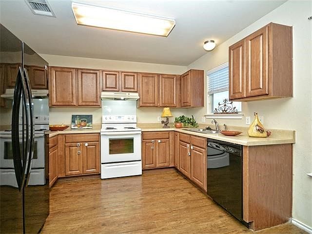 Laminate flooring, counter microwave, side by side refrigerator, window looking out to back yard