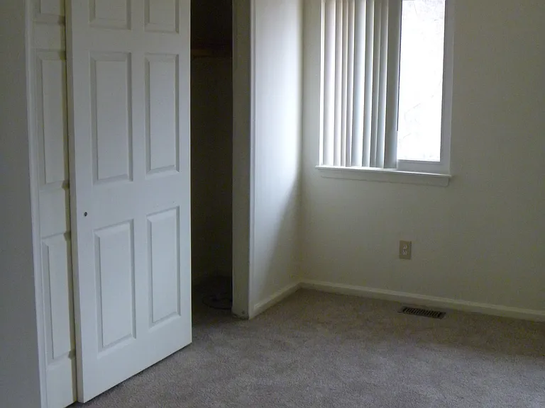 Upstairs bedroom facing yard with closet.