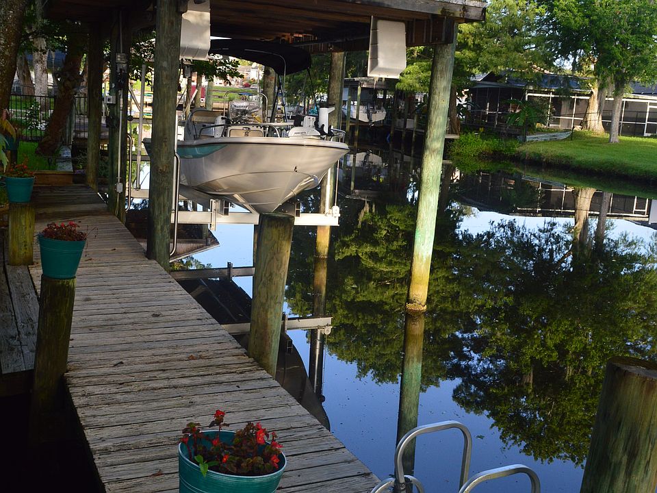 Private dock in backyard with boathouse and lift.