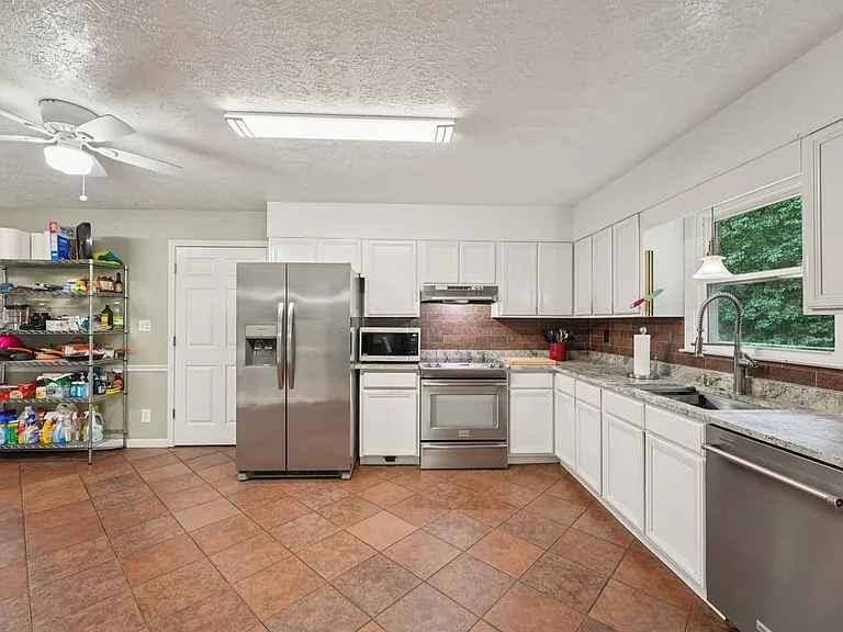 A welcoming culinary space filled with light and function, where classic white cabinets, sleek appliances, and earthy tile tones create a cozy yet refined atmosphere.