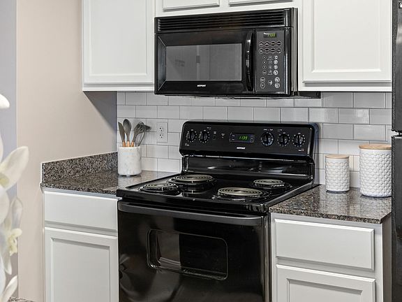 Cook with ease in a fully equipped kitchen featuring modern black appliances and granite countertops