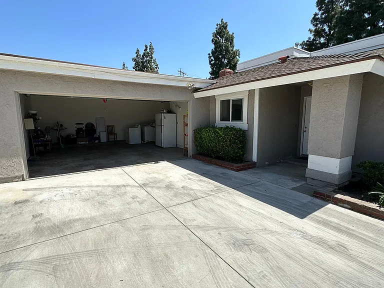 Front of house with oversized 2 car garage with washer and dryer and refrigerator included and storage in front of cars. Sectional garage door with opener.