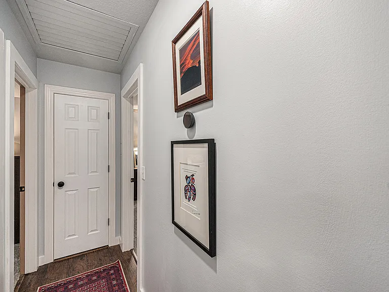 The hallway connecting the bedrooms features tasteful, understated decor, creating a serene and refined passage through the home.